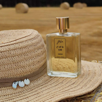 Perfume C'est la Fete de Giolor junto a sombrero en campos de trigo orgánico para alcohol para perfumería