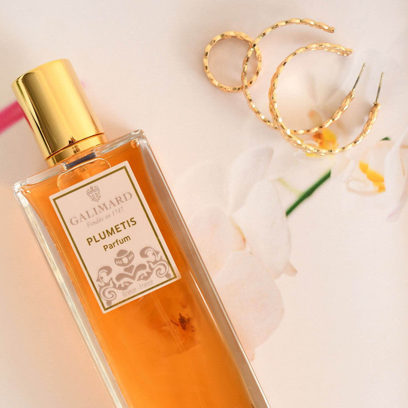 Perfume Plumetis de Galimard formato de 100 ml junto a unas joyas doradas 