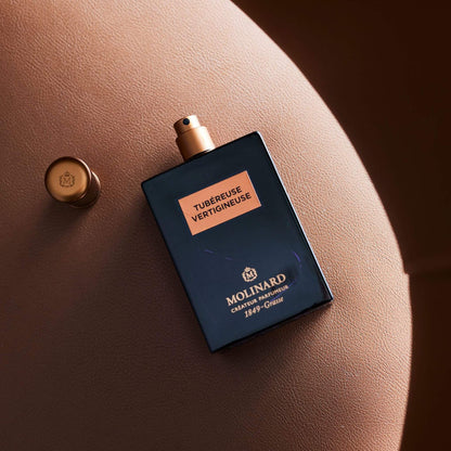 Perfume Tubéreuse Vertigineuse de Molinard sobre asiento de cuero café